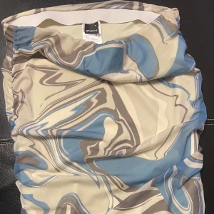 Mönstrad kjol från Gina Tricot - Säljer en snygg kjol från Gina Tricot med ett abstrakt mönster i blått, beige och brunt. Kjolen har en elastisk midja för extra komfort. Perfekt för att ge din outfit en unik touch!