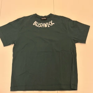 Mörkgrön Grön t-shirt från Bushwick - Snygg mörkgrön t-shirt från Bushwick med tryck på framsidan. Tillverkad i 100% bomull. Skriv om ni har frågor.
