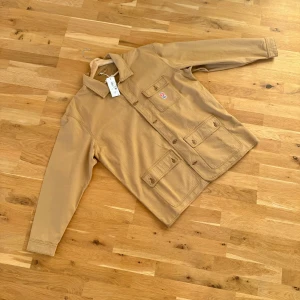 Ny beige jacka från Wrangler Workwear - Säljer en beige jacka/overshirt från Wrangler Casey Jones Workwear storlek XL. Jackan är från Wranglers workwear brand ”Casey Jones” i stil med Carhartt. Med knappar framtill och två stora fickor med lock. Helt ny med prislapp kvar.
