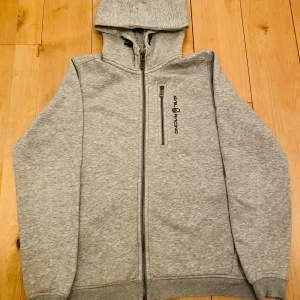 Grå hoodie från Sail Racing - Tjena, jag säljer sena snygga gråa hoodien från Sail Racing med dragkedja framtill och en praktisk huva. Perfekt för en avslappnad stil. Den har en diskret logga på bröstet och fickor. Säljer Den för 650kr nypris 1300kr