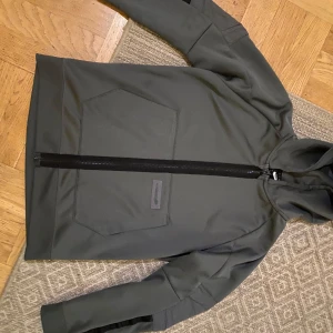 Grå  jacka från Nike - Säljer en stilren grå jacka från Nike med dragkedja framtill. Jackan har långa ärmar och en praktisk huva. Perfekt för en sportig look eller vardagsbruk.