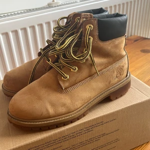 Bruna boots från Timberland - Äkta!!!! Mycket bra skick. Säljer ett par klassiska bruna boots från Timberland med svart vadderad krage och robust snörning i gult och svart. Skorna har en slitstark sula och är perfekta för höst- och vinterväder. De är tillverkade i skinn. Skriv för fler bilder.