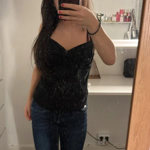 Svart linnetopp från Pipeline - Snygg svart linnetopp från Pipeline med smala axelband och en elegant draperad halslinje. Urringningen är pösig så man kan styla lite hur som helst🥰Denna top har inga skador och har nästan aldrig använts💕