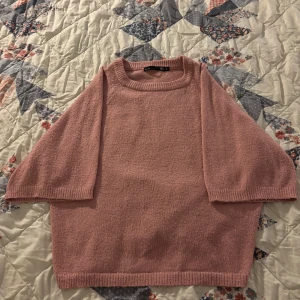 Rosa stickad tröja - Mysig rosa stickad tröja med trekvartsärm och rund halsringning. Perfekt för kyliga dagar och ger en avslappnad look. Passar bra till jeans eller kjol för en söt outfit.