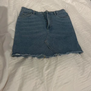 Blå jeanskjol  - Snygg blå jeanskjol. Perfekt för en avslappnad stil. Kjolen har en dragkedja fram. 