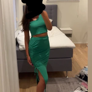 Grön oneshoulder set  - Snygg grön oneshoulder set med en tight passform. Kjolen har en slits och snörning på sidan som ger en extra touch. Perfekt för en somrig dag. 
