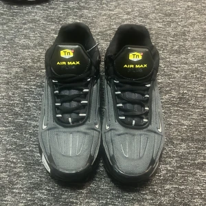 Nike Air Max Tn i svart - Snygga Nike Air Max Tn sneakers i svart med klassisk design och synlig Air Max-dämpning. Skorna har snörning och en robust sula för extra komfort. Perfekta för en sportig look.