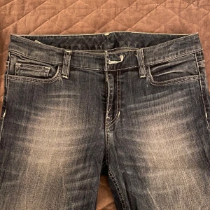 Mörkblå low waist jeans  - Snygga mörkblå low waist jeans med en klassisk femficksdesign. De har en lätt slitning på framsidan för en trendig look och är raka i passformen. Toppen skick förutom att en knapp fattas, vilket går att fixa och lite tråd på en av bakfickorna har gått upp (se bild) 💕 (vet inte vilket märke det är)                     Midja - 41 cm  Inneben - 87 cm