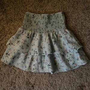 Blommig kjol från Gina Tricot - Söt blommig kjol från Gina Tricot med volanger och elastisk midja. Perfekt för en somrig look med det somriga mönstret och tunna materialet. Funkar såklart att ha närsomhelst på året. 