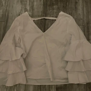 Zara vit blus  - En vit blus med lite öppen rygg, och kortare volang ärmar, den finns inte kvar längre. Den är i M men passar också S och Xs. Skriv om ni har frågor💓