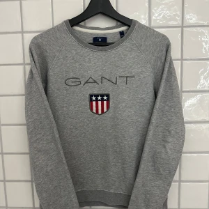 Grå sweatshirt från GANT - Ljusgrå GANT tröja, strl. M (160/84A) Damstorlek, passar både till tjej och kille.   Relaxed fit. Rund halsringning Broderad GANT-logotyp på bröstet  87% bomull 13% polyester   Köpt på GANT i Stockholm.
