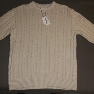 Beige stickad tröja från Kappahl - Säljer en stilren beige stickad tröja från Kappahl. Min moster köpte 2 men det passade inte min lillebror så jag säljer den. Tröjan har ett klassiskt flätmönster, ribbade muddar och 100% bomull 