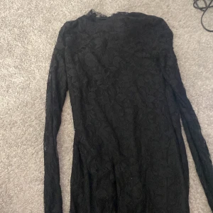 Svart spetsklänning från Vila - Elegant svart klänning från Vila i storlek S. Klänningen är långärmad och har ett vackert spetsmönster som ger en sofistikerad look. Perfekt för speciella tillfällen.