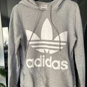 Grå hoodie från Adidas - Säljer en grå hoodie från Adidas, men en liten fläck på ryggen (går säkert bort om man tvättar ordentligt)🩶Pris går att diskutera vid snabb affär 