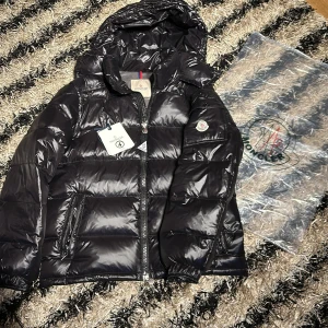 Svart Moncler Maya - Säljer en snygg svart dunjacka från Moncler med glansig finish. Jackan är perfekt för kyliga dagar med stil och är dessutom i nyskick. Storlek 4 (L) NFC- Scan är fungerande! Kan tänka mig att gå ner i pris vid en snabb och smidig affär! Har du några frågor eller funderingar tveka inte på att höra av dig!