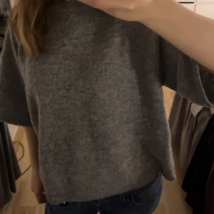 Grå stickad tröja - Mysig grå stickad tröja med en loose passform och trekvartsärmar. Perfekt för kyligare dagar och enkel att matcha med jeans eller kjol.