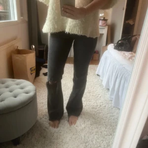 Svarta jeans med slitningar - Snygga svarta jeans med slitningar på knäet. De har en bootcut-stil, vilket ger en trendig stil. Från Gina tricot i storlek 36