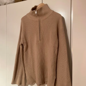 Beige stickad tröja - Superfin beige tröja med halv dragskedja! Lite större i armarna, stor i strl. Använd 1-3 gånger max därav i nyskick. Liten slits på sidan