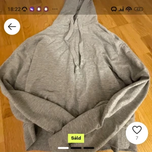 Grå hoodie - Mysig grå hoodie i mjukt material. Perfekt för chill dagar eller när du bara vill vara bekväm. Den har en klassisk design med huva och dragsko, samt långa ärmar och ribbade muddar. (Köpt på lick men var för liten) 