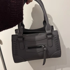 grå väska  - En grå väska från gina tricot! har inte använt den så många gånger. ordinarie pris är 399kr, och finns inte kvar på hemsidan! 