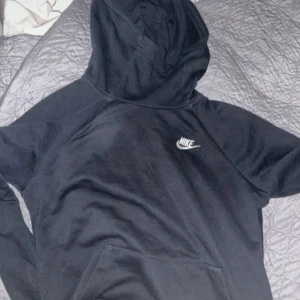 Svart hoodie från Nike - Säljer en svart hoodie från Nike i storlek L. Den är superbekväm och perfekt för både träning och chill. Hoodien har en klassisk design med Nike-loggan på bröstet. Perfekt för höst och vinter!