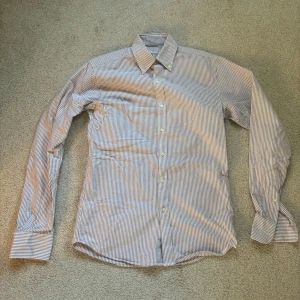 Skjorta John Henric - Randig skjorta i vit och brun från John Henric, passformen är relativt slimmad, skjortan är i utmärkt skick 