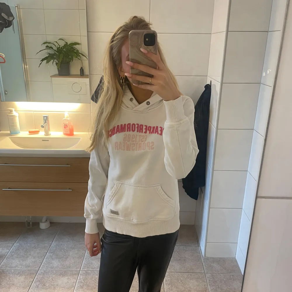 En vit fin hoodie med rosa text från peak performance storlek s. Hoodies.