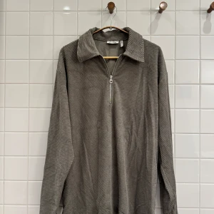 Grå oversized tröja från Weekday - Säljer en supermjuk och bekväm grå tröja från Weekday. Den har en dragkedja framtill och en snygg krage. Perfekt för en avslappnad stil och passar till alla tillfällen. Tröjan är i oversized passform vilket gör den extra mysig att bära.