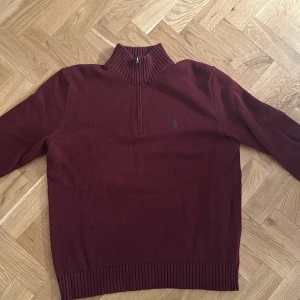 Vinröd tröja från Polo Ralph Lauren - Säljer en snygg vinröd tröja från Polo Ralph Lauren. Den har en dragkedja vid halsen och är gjord i ett mjukt material. Perfekt för höst och vinter! Den har långa ärmar och en liten grön logga på bröstet. Passar både till vardags och lite finare tillfällen.