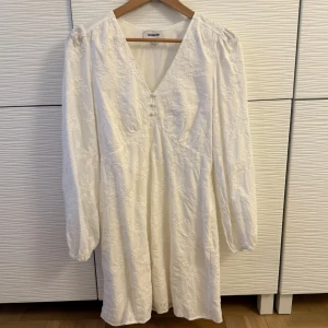 Vit studentklänning - Elegant vit klänning från Kappahl med v-ringning och långa ärmar. Klänningen har ett vackert broderat blommönster. Perfekt för vår och sommar. Dragkedja på sidan. Väldigt fin att ha som studentklänning. Endast använd en gång. Som ny. Storlek S.