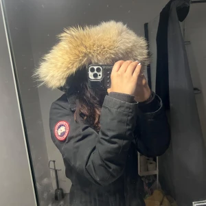 Canada goose dam XS/S - Säljer en svart vinterjacka från Canada Goose med päls. Jackan har en klassisk design med lång ärm och är perfekt för kalla dagar XS men passar även S. Den har en tydlig logotyp på ärmen. Bra skick på jackan. Äkta.