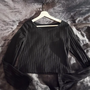 Svart ribbad tröja - Snygg svart ribbad tröja med långa ärmar. Perfekt för en stilren look. Passar bra till både jeans och kjol.