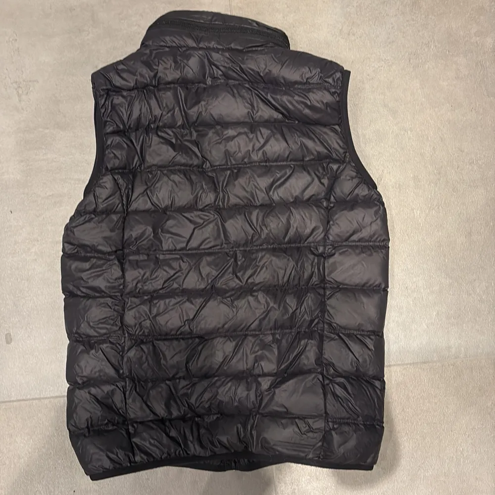 Snygg svart dunväst från Emporio Armani med dragkedja vid nacken där luva finns. Fin att ha till sommaren och blåsiga tillfällen. Passar knappt mig som är 176 cm men beror på passform. Nypris 1399kr. Takit.