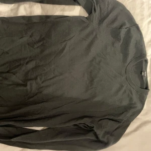 Mörkgrå tröja från Uniqlo - Säljer en stilren mörkgrå tröja från Uniqlo. Tröjan är långärmad och har en rund halsringning. Perfekt för en minimalistisk look. 100% merinoull!