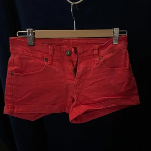 Röda shorts från Amisu - Snygga röda shorts från Amisu med klassisk femficksdesign och knappgylf. Perfekta för sommardagar och avslappnade tillfällen. De har en lågmidjad passform och är tillverkade i ett bekvämt material.