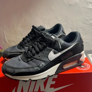 Svarta Nike Air Max sneakers - Snygga svarta Nike Air Max sneakers med vit sula och ikonisk Nike-logga i vitt. Skorna har snörning och en bekväm passform, perfekt för vardagsbruk. Luftdämpning i sulan ger extra komfort. 7/10 skick!