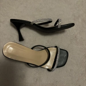 Svarta klackskor med glittriga remmar - Eleganta svarta klackskor med glittriga remmar. Perfekta för en kväll ute eller en speciell tillställning. Skorna har en stilren design med en bekväm klackhöjd.