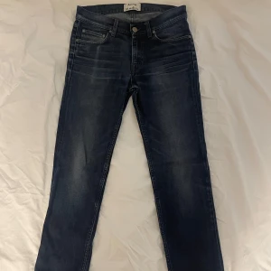 Mörkblå jeans från Acne Studios - Snygga mörkblå jeans från Acne Studios i modellen Ace Oreo. Tillverkade i en bomullsblandning med en touch av elastan för extra komfort. Klassisk femficksdesign med knappgylf och bälteshällor.