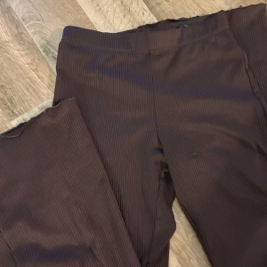 Bruna ribbade leggings - Snygga bruna leggings med ribbad textur. Perfekta för en bekväm och stilren look. De har en elastisk midja för extra komfort.