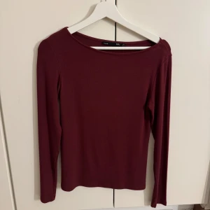 Vinröd ribbad topp - Säljer en stilren vinröd ribbad topp med långa ärmar. Perfekt för höst och vinter, med en bekväm passform som passar till många olika outfits.