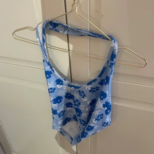 Blå blommig halter neck  - Snygg blå halterneck med vita blommor. Perfekt för sommaren!