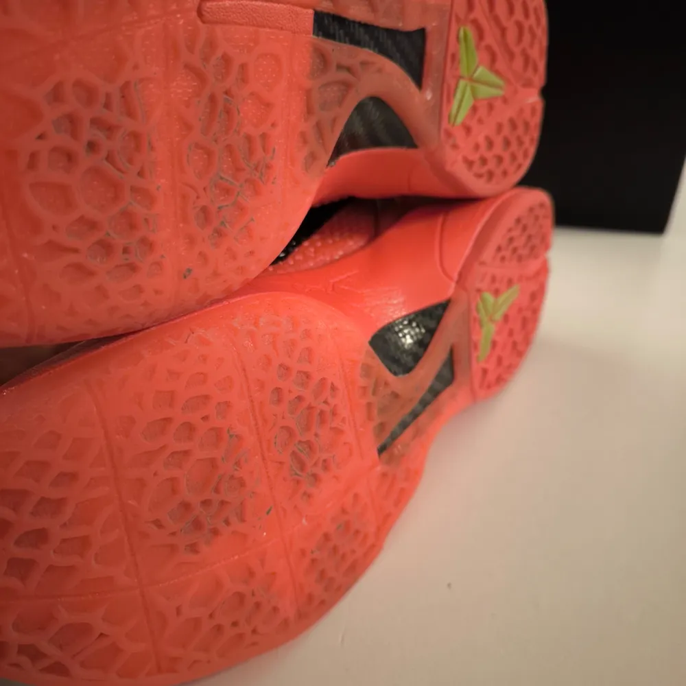 Nike Kobe 6 Protro Reverse Grinch. Snygga röda sneakers med gröna snören och detaljer. Skorna har en unik textur och en svart sula med gröna logotyper. Perfekta för den som vill sticka ut med färgglada skor.. Kengät.