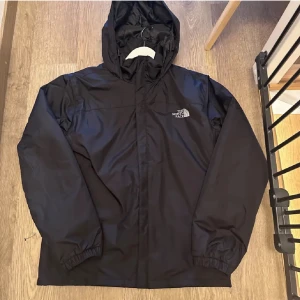 The North Face regnjacka - Säljer en svart regnjacka från The North Face. Jag säljer den då jag tycker den inte passa mig riktigt. Storleken är S. Det finns inga skador på jackan och den är i mycket fint skick. Tveka inte o skriva om ni har några frågor.  