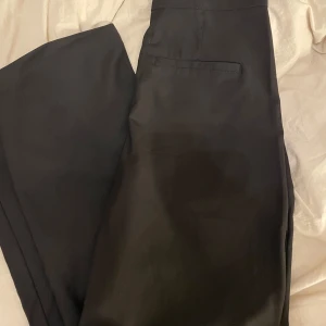 Svarta kostymbyxor från 157 - Snygga svarta kostymbyxor från 157 i storlek XS. Byxorna har en klassisk design med hög midja och raka ben. Perfekta för en stilren look. Sparsamt använda 