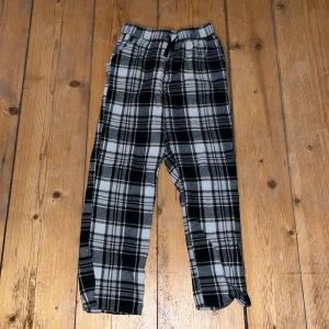 Rutiga pyjamasbyxor från Kappahl - Säljer ett par bekväma och stiliga rutiga byxor från Kappahl. Byxorna har en elastisk midja med snörning och är perfekta för en avslappnad look. De är i svart, grått och vitt med ett klassiskt rutmönster. Nästan aldrig använda. Säljer pga-för små! Kontakta för mer information!!!