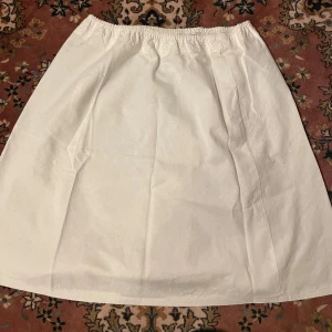 Vit medellång kjol - Vit kjol med resår i midjan utan fläckar, går ner lite under knäna och även om storleken är XL så skulle jag säga att den passar M/L