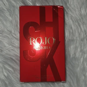 Röd parfymflaska från Shakira 80ml - Säljer en elegant röd parfymflaska från Shakira med namnet 'Rojo'. Flaskan har en fyrkantig form med ett dekorativt lock i svart och guld. Sprejat max 5 gånger. Fick den som present den är köpt på flygplatsen för runt 600kr. Använder inte den eftersom jag gillar mer Vanilj parfymer men den luktar otroligt gott. 