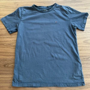 Blå t-shirt från Tommy Hilfiger - Snygg blå t-shirt från Tommy Hilfiger med en liten broderad logga på bröstet. Fint skick, inga fläckar. Storlek 146-152