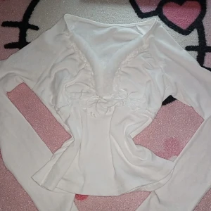 Gullig vit topp - Söt vut top med fluff och spets. Långa ärmar, strech, mjuk och fitting. Söta snören man kan dra för att göra den mera tight. Använd 3-4 gånger och är fortfarande i perfect skick. Köpt för 249kr säljer för 230kr