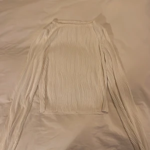Vit ribbad långärmad topp - Säljer en stilren vit ribbad topp med långa ärmar. Perfekt för en minimalistisk look och passar till många olika outfits. Toppen har en enkel design med en bekväm passform.